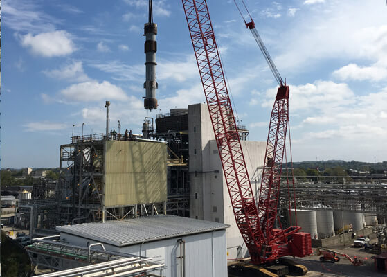 Crane moving large equipment at a 5 story building